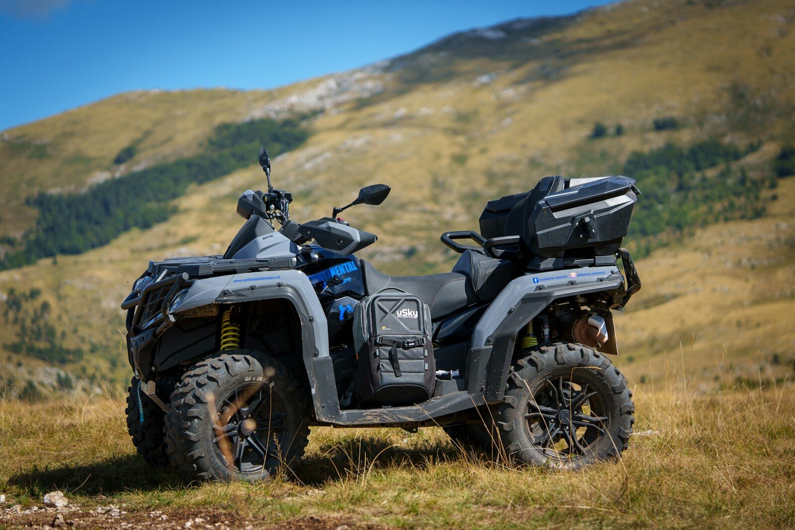 A four - wheeler parked in a field with mountains in the background